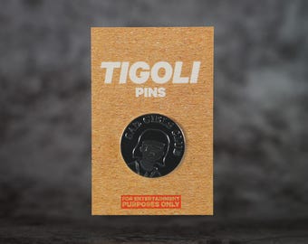 以下が含まれることがあります： Tigoli Pinsのシルバーカラーのピン。円形のデザインで、女の子の漫画のイメージの周りに「BAD GIRLS CLUB」の文字が書かれています。ピンは「FOR ENTERTAINMENT PURPOSES ONLY」の文字が入った茶色のカードに取り付けられています。