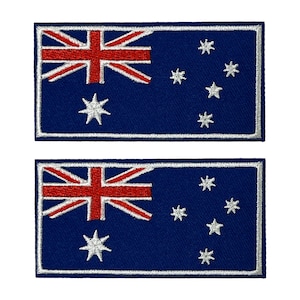 Könnte beinhalten: Zwei rechteckige Aufnäher mit der australischen Flagge. Das Design zeigt einen blauen Hintergrund, den Union Jack in der oberen linken Ecke, einen großen weißen siebenzackigen Stern und mehrere kleinere weiße Sterne. Die Ränder sind weiß umrandet.