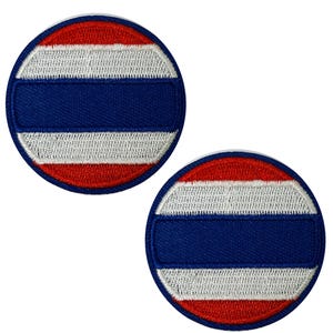 May include: Two circular patches featuring the flag of Thailand. Each patch has a blue central stripe, flanked by white stripes above and red stripes below, all within a red border. The patches are embroidered.