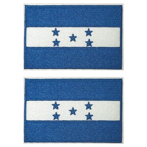 May include: Two embroidered patches depicting the flag of Honduras. Each patch has a blue background with a white horizontal stripe. Five blue stars are centred on the white stripe.