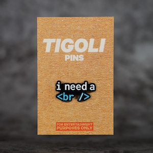 May include: A rectangular pin on a brown card with the text "TIGOLI PINS" in white. The pin reads "i need a <br />" in black and blue. The bottom of the card reads "FOR ENTERTAINMENT PURPOSES ONLY" in red.