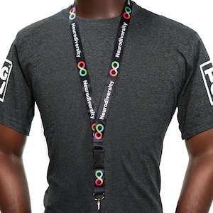 May include: A dark grey t-shirt with a black lanyard. The lanyard features the word "Neurodiversity" and a colourful infinity symbol. The t-shirt has a white logo on the left sleeve.