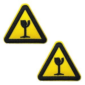 May include: Two yellow triangular patches with black borders and a black graphic of a broken wine glass. The patches are embroidered and likely iron-on or sew-on for clothing or accessories. The patches are a warning symbol.