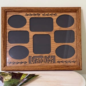 May include: A wooden picture frame with eight openings for photos. The frame is brown and has the word "Grandkids" engraved on the bottom.