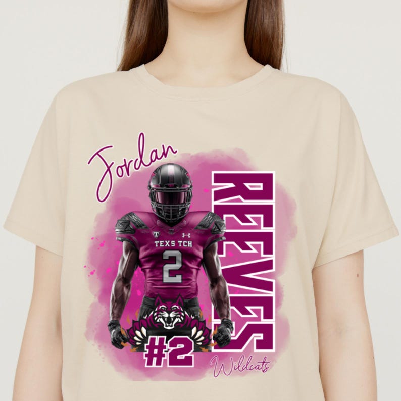 K&ouml;nnte beinhalten: Beiges T-Shirt mit einem Footballspieler-Motiv. Die Grafik enth&auml;lt den Namen "Jordan" in Schreibschrift, den Namen "REEVES" in lila Blockbuchstaben und die Nummer "2". Der Spieler tr&auml;gt eine weinrote Uniform und einen Helm.