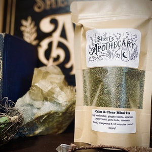 May include: A brown paper bag with a white label that reads "Sheri's Apothecary" and "Calm & Clear Mind Tea". The label lists the ingredients: holy basil (tulsi), gingko biloba, spearmint, peppermint, gotu kola, and rosemary. The label also includes instructions: "Step 2 teaspoons 8-10 minutes covered Enjoy!"