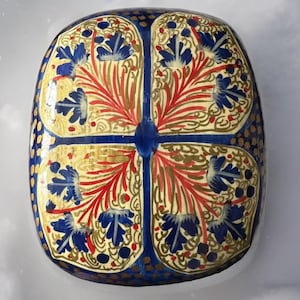 Op de afbeelding: Decoratieve, rechthoekige doos met een blauw, goud en rood bloemmotief. De doos heeft een symmetrisch patroon met blauwe bloemen, rode bladeren en gouden accenten. De randen zijn donkerblauw met gouden stippen.