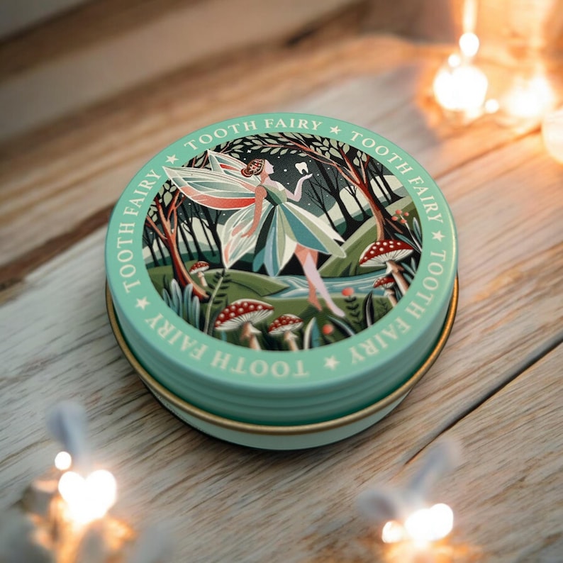 May include: A green round tin with a gold rim. The tin has a whimsical illustration of a fairy flying through a forest with mushrooms and a stream. The text "Tooth Fairy" is repeated around the edge of the tin.