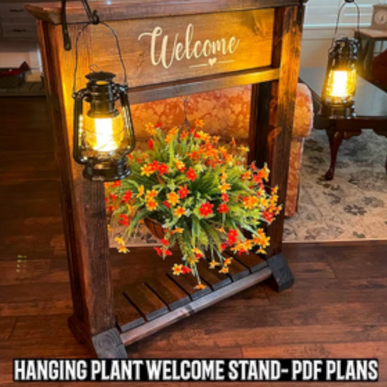 May include: A wooden hanging plant stand with a welcome sign and two lanterns. The stand has a shelf and is decorated with a hanging plant with orange and yellow flowers.