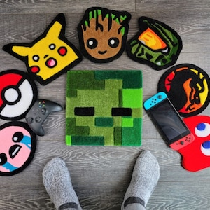 May include: A collection of colorful, hand-crafted felt floor mats featuring various characters and designs. The mats include a green monster, a yellow Pikachu, a red and blue Pac-Man, a brown Groot, a green and black ninja, a blue and green Nintendo Switch, and a red and white ghost.