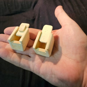 May include: Two small wooden boxes with lids. The boxes are unfinished and have a natural wood color. The boxes are about 2 inches tall and 1 inch wide.