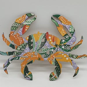 May include: A decorative wooden crab with a colourful floral pattern in shades of yellow, orange, green, and purple.