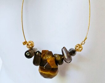 May include: Gold hoop earrings with a cluster of brown and gold tiger's eye stones and dark brown beads.