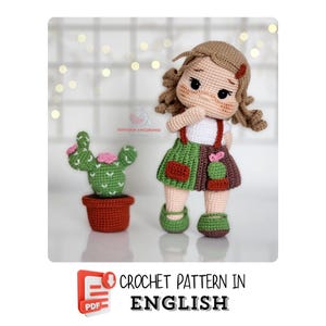 Puede incluir: Patrón de crochet para una muñeca de niña con cabello castaño y un vestido verde y marrón. La muñeca sostiene un pequeño cactus en una maceta. El patrón está disponible en formato PDF y está escrito en inglés.