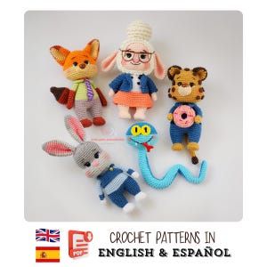 May include: A selection of crocheted amigurumi characters, featuring a fox, a sheep, a tiger, a bunny, and a snake. The figures are in various colours and outfits. The image also includes text that says "CROCHET PATTERNS IN ENGLISH & ESPAÑOL".