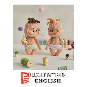 May include: Two crocheted baby dolls with light skin tones, wearing white diapers with yellow accents. One doll holds a carrot and a white bunny, the other holds a white bunny. The dolls have brown and blonde yarn hair. The image includes spools of thread and the text "CROCHET PATTERN IN ENGLISH."
