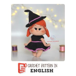 May include: A crocheted doll of a witch with red hair, wearing a black dress and a black witch hat with a pink band. The doll has a light skin tone and is standing in front of a blurred background. The text "CROCHET PATTERN IN ENGLISH" is at the bottom.