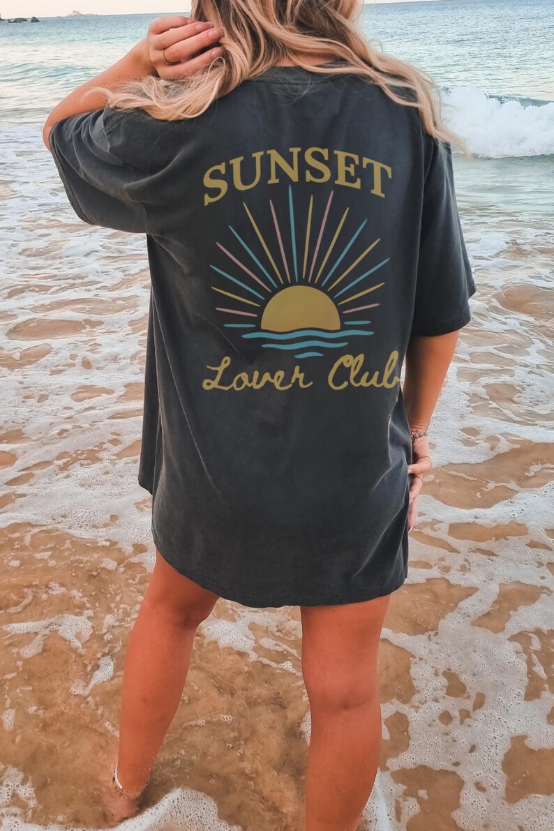 May include: A black oversized t-shirt with a graphic of a sunset and the text "Sunset Lover Club" on the back.