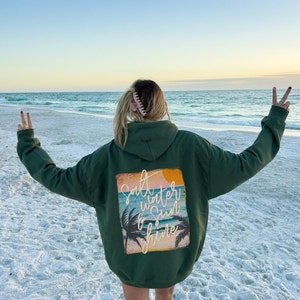 May include: A green hooded sweatshirt with a graphic print on the back that says "Salt Water & Sun Shine" with a palm tree and sunset design.