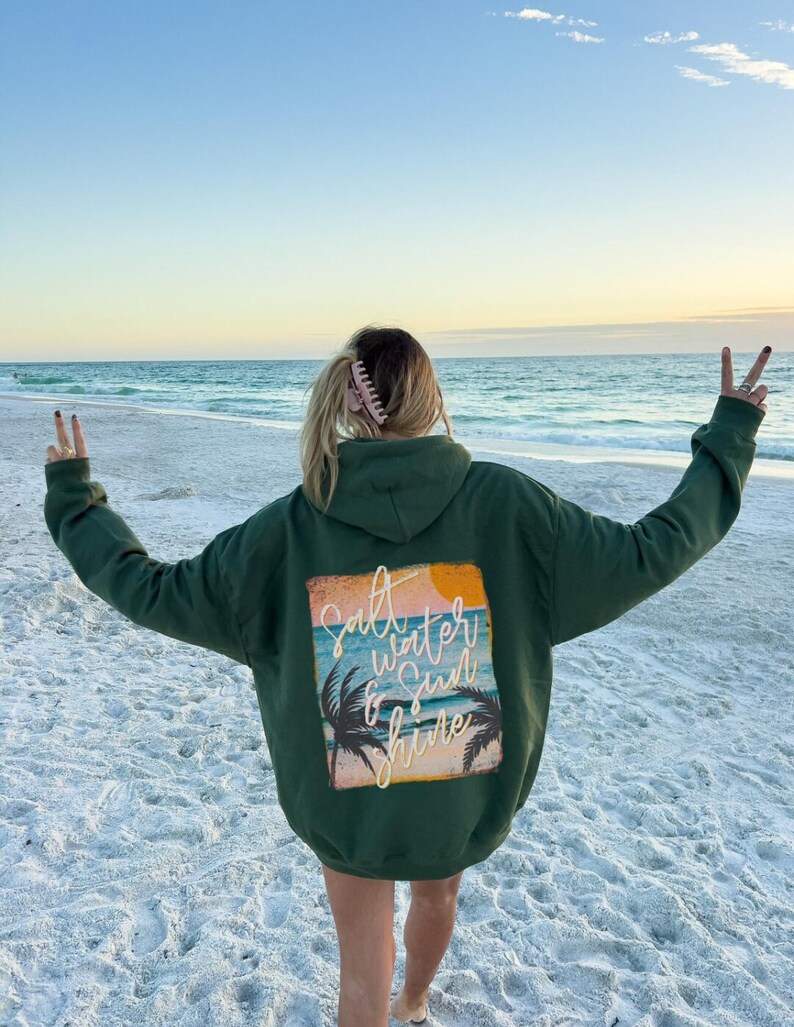 May include: A green hooded sweatshirt with a graphic print on the back that says "Salt Water & Sun Shine" with a palm tree and sunset design.