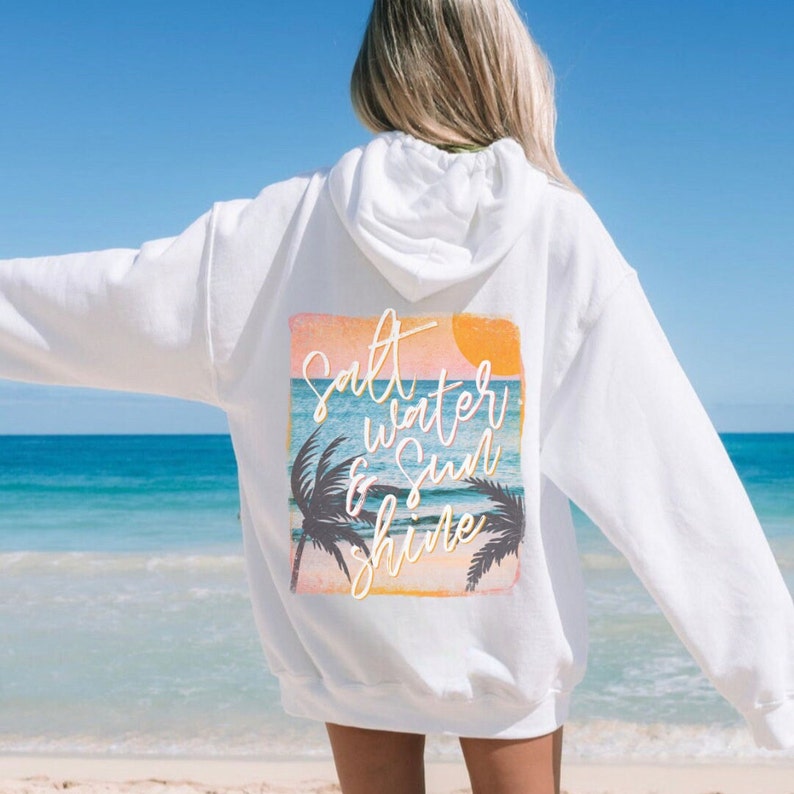 May include: White hoodie with a graphic print on the back that says "Salt Water & Sun Shine" with a sunset and palm trees.