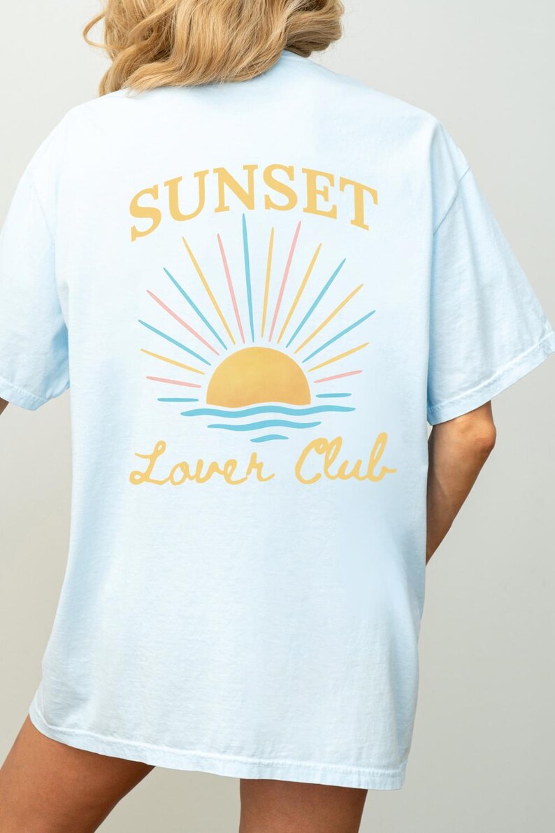 May include: Light blue t-shirt with a graphic of a sunset over the ocean and the text "Sunset Lower Club" in yellow.