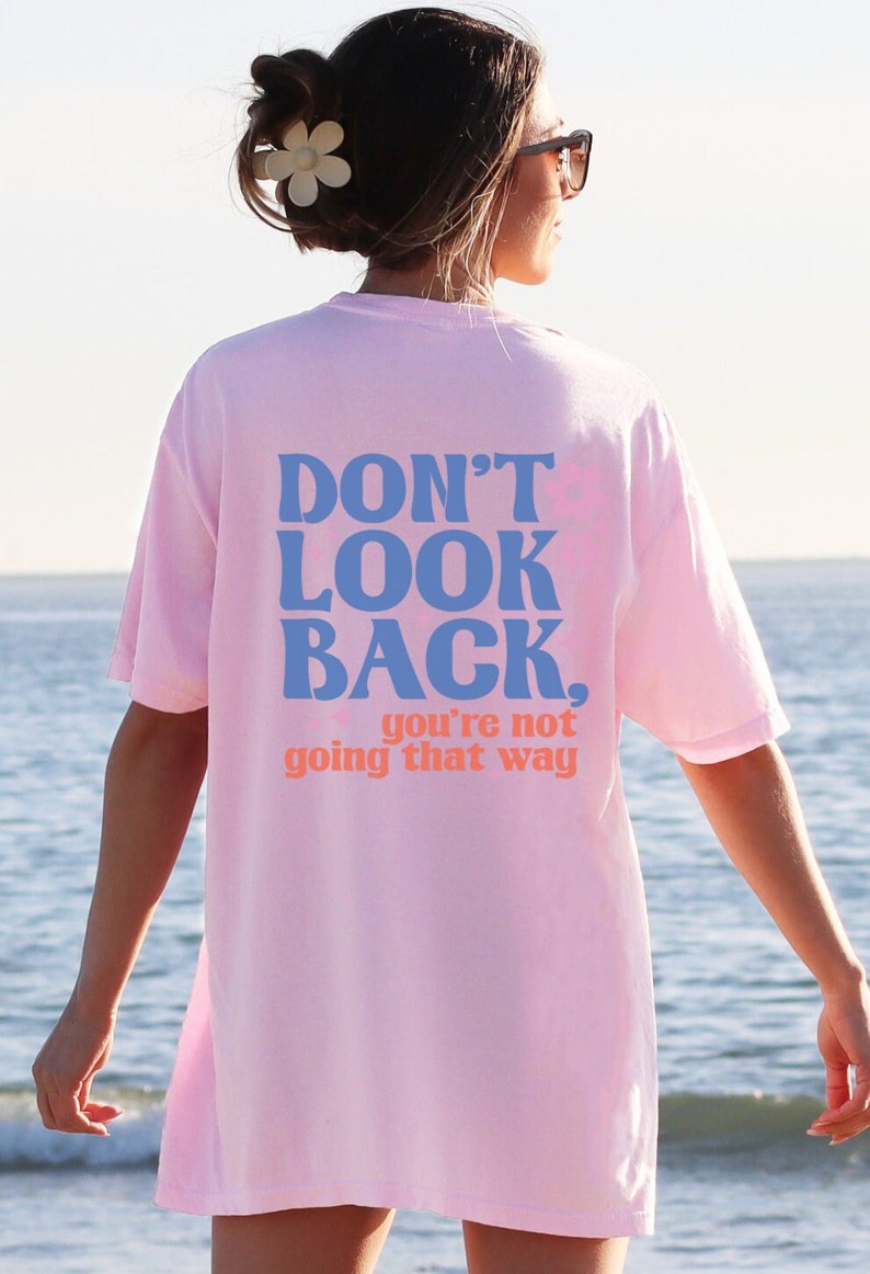 May include: Pink oversized t-shirt with the text "DON'T LOOK BACK. you're not going that way" in blue and orange lettering.