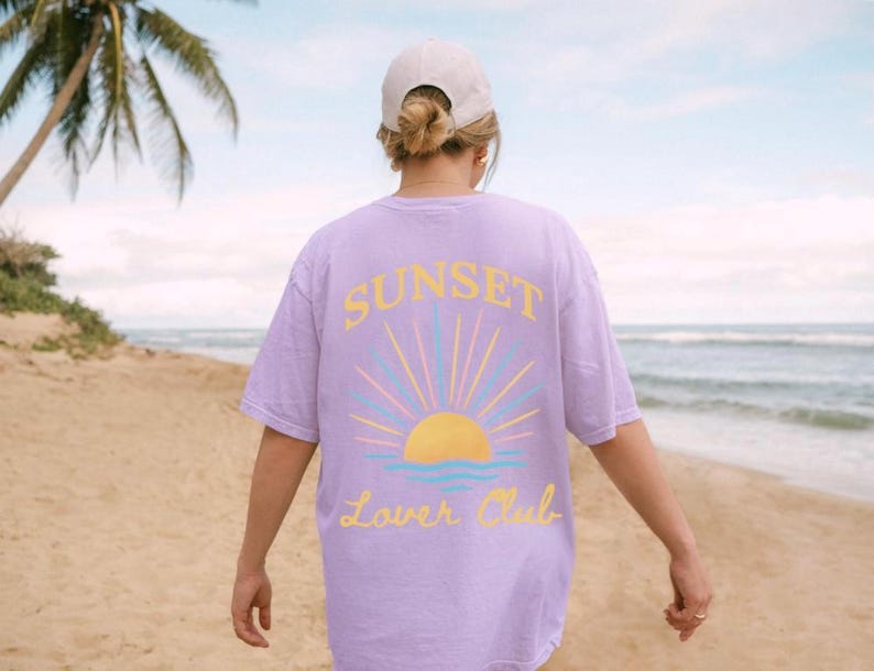 May include: A lavender t-shirt with a graphic of a sunset and the text "Sunset Lover Club".