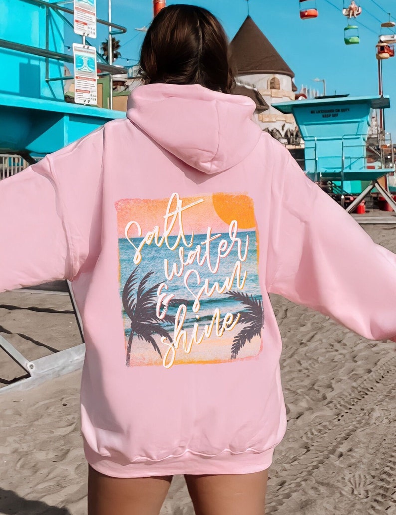 May include: Pink hoodie with a graphic print of a sunset, palm trees, and the text "Salt Water & Sun Shine".