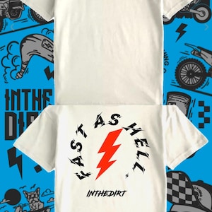 Op de afbeelding: Twee witte t-shirts met zwarte en rode graphics. Eén shirt heeft "INTHEDIRT" en een bliksemschicht. De andere heeft "FAST AS HELL" rond een bliksemschicht en "INTHEDIRT". De achtergrond is blauw met motorfiets illustraties.