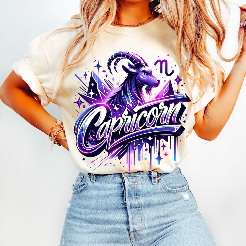 Peut inclure: Un t-shirt blanc avec un motif graphique violet et bleu repr&eacute;sentant un signe du zodiaque Capricorne avec le mot "Capricorne" dans une police stylis&eacute;e. Le motif comprend &eacute;galement des &eacute;toiles et un effet de goutte &agrave; goutte.