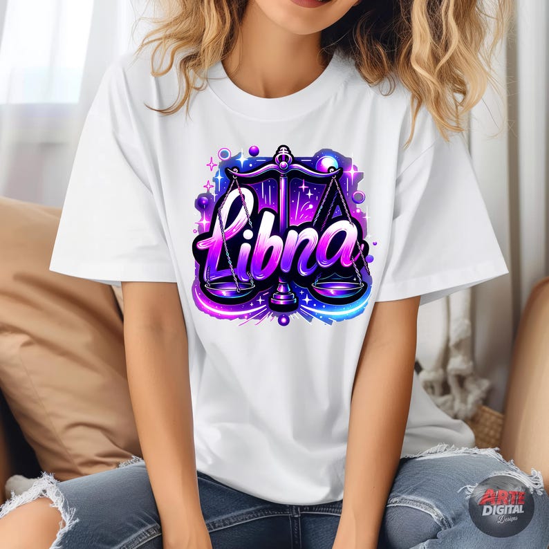 Peut inclure: T-shirt blanc avec un graphique violet et bleu d'un symbole du zodiaque Balance et le mot "Balance" dans une police stylis&eacute;e.