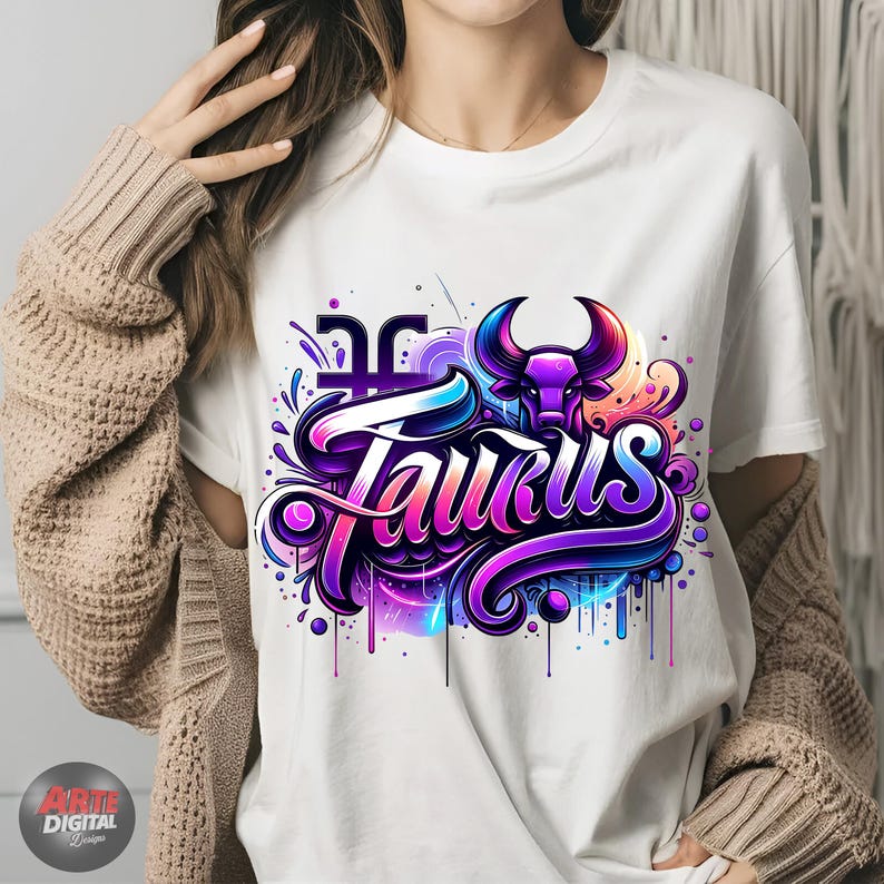 Peut inclure: T-shirt blanc avec un motif graphique color&eacute; repr&eacute;sentant le mot "Taurus" dans une police stylis&eacute;e avec une t&ecirc;te de taureau violette et un symbole astrologique.
