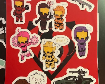 Op de afbeelding: Een verzameling cartoonstickers op een rode achtergrond, met personages in verschillende kleuren, waaronder rood, bruin, oranje, roze, geel en paars. De stickers tonen figuren in harnassen, wapens en voertuigen. Tekst bevat "RED TEAM" en tekstballonnen.