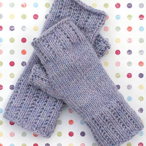 Puede incluir: Un par de guantes sin dedos de punto de color morado. Los guantes están hechos con un patrón de punto texturizado.