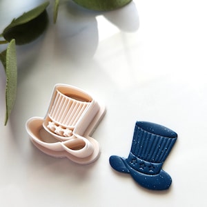 May include: Two Uncle Sam top hat cookie cutters, one white plastic and one blue with glitter.