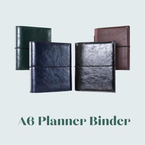 Könnte beinhalten: Eine Auswahl an A6-Planer-Bindern in verschiedenen Farben, darunter Grün, Marineblau, Schwarz und Braun. Jeder Binder hat eine strukturierte, lederähnliche Oberfläche und einen schwarzen elastischen Verschluss. Der Text "A6 Planner Binder" ist unten zu sehen.