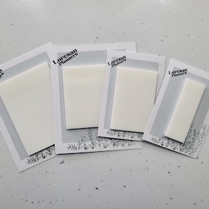 Può includere: Quattro post-it rettangolari bianchi su biglietti con bordo grigio e design floreale. Il testo "Loresan Planners" è stampato in nero in alto a sinistra di ogni biglietto. I post-it variano di dimensioni.