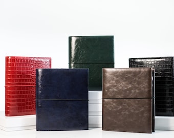 May include: Five leather-bound journals in different colors, including red, green, blue, brown, and black. The journals have elastic bands to keep them closed.
