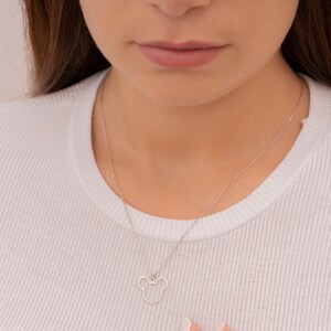 May include: A silver chain necklace with a small, open-circle pendant shaped like a cartoon mouse head.