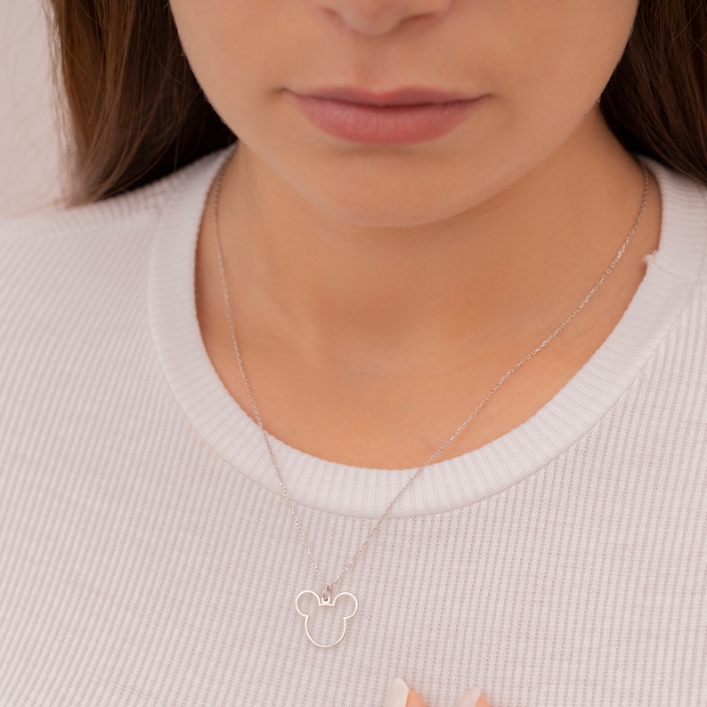 May include: A silver chain necklace with a small, open-circle pendant shaped like a cartoon mouse head.