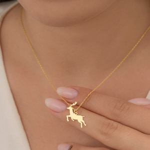 May include: A gold chain necklace with a delicate deer pendant. The deer is facing right and has a simple, elegant design.