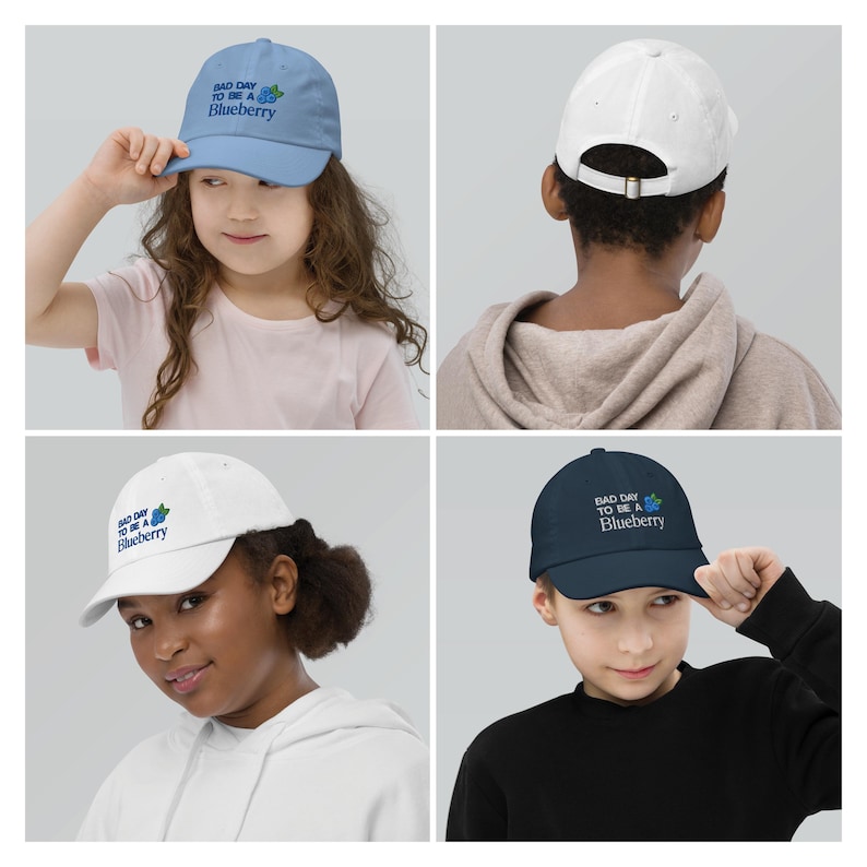 May include: Four baseball caps in light blue, white, and navy, each with the text "BAD DAY TO BE A Blueberry" and a blueberry graphic. The caps are shown on children. The caps have adjustable straps.