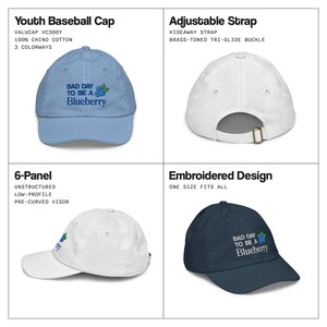 May include: A selection of youth baseball caps in different colours. Each cap has an embroidered design with the text "BAD DAY TO BE A Blueberry" and a blueberry graphic. Features include an adjustable strap and a pre-curved visor.