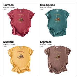 Może przedstawiać: Cztery koszulki Comfort Colors 1717 w kolorach Crimson, Blue Spruce, Mustard i Espresso. Każda koszulka ma grafikę żaby z napisem "'tis medicinal" i "Lord".