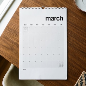 May include: A white wall calendar with black text and a wire-bound top. The page displays the month of March with a grid of days from Sunday to Saturday, numbered dates, and a section labeled NOTES at the bottom left corner of the page.