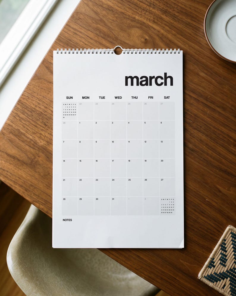 May include: A white wall calendar with black text and a wire-bound top. The page displays the month of March with a grid of days from Sunday to Saturday, numbered dates, and a section labeled NOTES at the bottom left corner of the page.