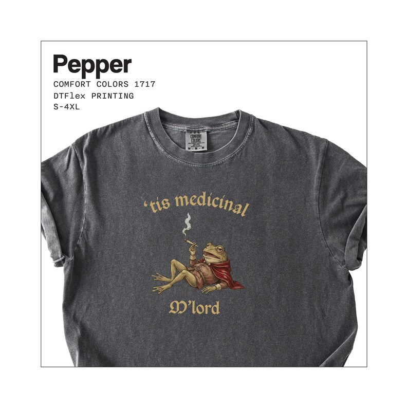 Może przedstawiać: Ciemnoszara koszulka z grafiką żaby palącej papierosa, w pelerynie i napisem "'tis medicinal M'lord". Koszulka ma r&oacute;wnież napis "Pepper", "COMFORT COLORS 1717", "DTFlex PRINTING" i "S-4XL".