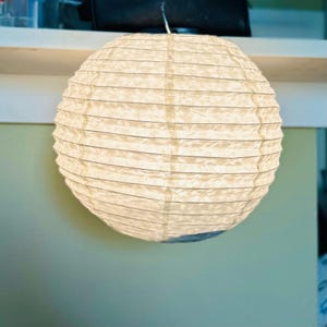 Handmade Lokta paper lamp shade with bamboo frame – eco-friendly Japanese-style lighting. Orb-shaped Lokta paper pendant lamp in medium size– sustainable minimalist decor. Neutral tone paper pendant light – perfect for Japandi and zen-inspired interiors. Set of handmade paper lamp shades in assorted sizes – minimalist home decor. Handmade Nepalese Lokta Paper Lamp Shade with Bamboo Frame - Sustainable, Durable, Lightweight. Embossed Petals, Leaves.