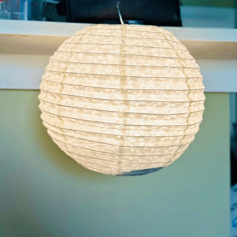 Handmade Lokta paper lamp shade with bamboo frame – eco-friendly Japanese-style lighting. Orb-shaped Lokta paper pendant lamp in medium size– sustainable minimalist decor. Neutral tone paper pendant light – perfect for Japandi and zen-inspired interiors. Set of handmade paper lamp shades in assorted sizes – minimalist home decor. Handmade Nepalese Lokta Paper Lamp Shade with Bamboo Frame - Sustainable, Durable, Lightweight. Embossed Petals, Leaves.